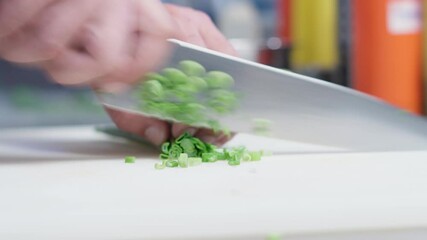 Wall Mural - The chef cutting spring onion using sharp knife on a chopping board.