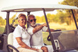  Golfers couple are riding in a golf cart and talking.