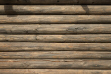 The Wall Of An Old Wooden House Made Of Darkened Weathered Logs. Traditional Russian Log Hut.