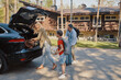 © gstockstudio - Happy family packing stuff in car and smiling while standing in front of the house