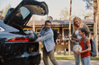 © gstockstudio - Happy family packing stuff in car and smiling while standing in front of the house