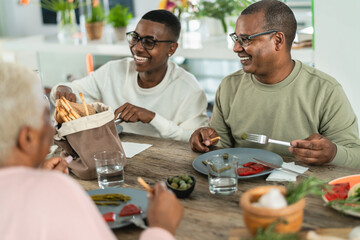 Happy afro Latin family eating healthy lunch with fresh vegetables at home - Food and parents unity concept