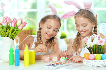  sisters wearing rabbit ears decorating  Easter eggs at home