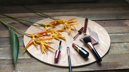 Set of makeup,cosmetics,Red matte lipstick and beautiful Heliconia flowers bouquet on wood background,with natural dimly light,free space for your text design,selective focus.