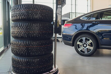 4 New Tires That Change Tires In The Auto Repair Service Center, Blurred Background, The Background Is A New Car In The Stock Blur For The Industry, A Four-wheeled Tire Set At A Large Warehouse.