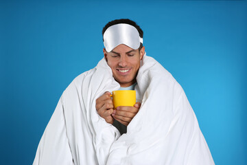 Canvas Print - Man wrapped in blanket holding cup on blue background