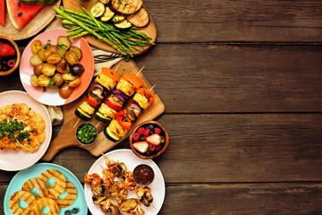 Wall Mural - Vegan summer bbq or picnic side border. Above view over a dark wood background. Grilled fruit and vegetables, skewers, cauliflower steak and vegetarian sides. Copy space. Meat substitute concept.