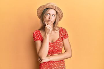 Sticker - Beautiful caucasian woman wearing summer hat thinking concentrated about doubt with finger on chin and looking up wondering