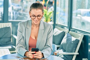 Sticker - Young blonde businesswoman smiling happy using smartphone at the coffee shop.