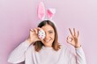 © Krakenimages.com - Young beautiful woman wearing cute easter bunny ears holding egg doing ok sign with fingers, smiling friendly gesturing excellent symbol