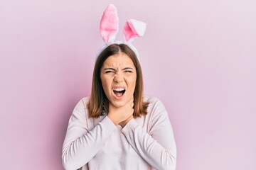 Canvas Print - Young beautiful woman wearing cute easter bunny ears shouting and suffocate because painful strangle. health problem. asphyxiate and suicide concept.