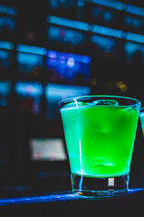 Glass of green cocktail on bar background