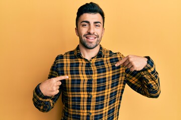 Young hispanic man wearing casual clothes looking confident with smile on face, pointing oneself with fingers proud and happy.