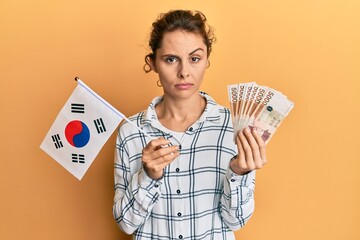 Poster - Young brunette woman holding south korean won banknotes skeptic and nervous, frowning upset because of problem. negative person.