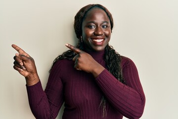 Sticker - African young woman wearing casual clothes smiling and looking at the camera pointing with two hands and fingers to the side.