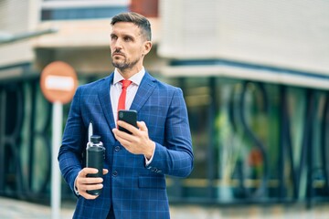 Wall Mural - Young caucasian businessman with serious expression using smartphone at the city.