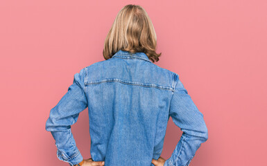 Wall Mural - Caucasian man with blond long hair wearing casual denim jacket standing backwards looking away with arms on body