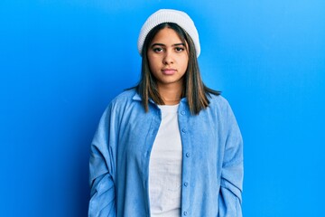 Sticker - Young latin woman wearing cute wool cap relaxed with serious expression on face. simple and natural looking at the camera.