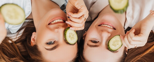 Wall Mural - two girls make homemade face and hair beauty masks. cucumbers for the freshness of the skin around t