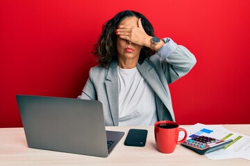 Sticker - Beautiful middle age woman working at the office drinking a cup of coffee covering eyes with hand, looking serious and sad. sightless, hiding and rejection concept