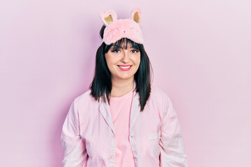 Sticker - Young hispanic woman wearing sleep mask and pajama looking positive and happy standing and smiling with a confident smile showing teeth