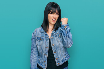 Canvas Print - Young hispanic woman wearing casual clothes angry and mad raising fist frustrated and furious while shouting with anger. rage and aggressive concept.