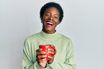 Poster - Young african american girl drinking a cup of coffee smiling and laughing hard out loud because funny crazy joke.