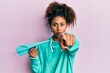 © Krakenimages.com - Beautiful african american woman with afro hair holding paper airplane pointing with finger to the camera and to you, confident gesture looking serious