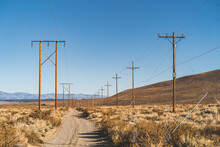 Dirt Road Along Power Poles In California High Desert Against Blue Sky