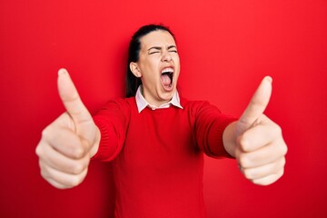 Canvas Print - Young hispanic woman doing thumbs up positive gesture angry and mad screaming frustrated and furious, shouting with anger. rage and aggressive concept.