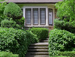 Steps leading to front door of house, surrounded by dense shrubbery