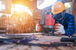 © somchai20162516 - Close-up of an Asian carpenter using a hacksaw in a sawmill.