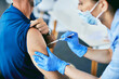 Close-up of nurse vaccinating a man against coronavirus at medical clinic.
