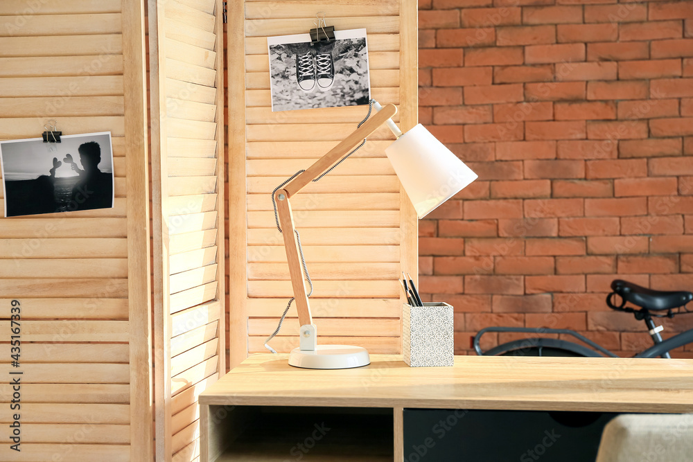 Modern lamp and folding screen near brick wall