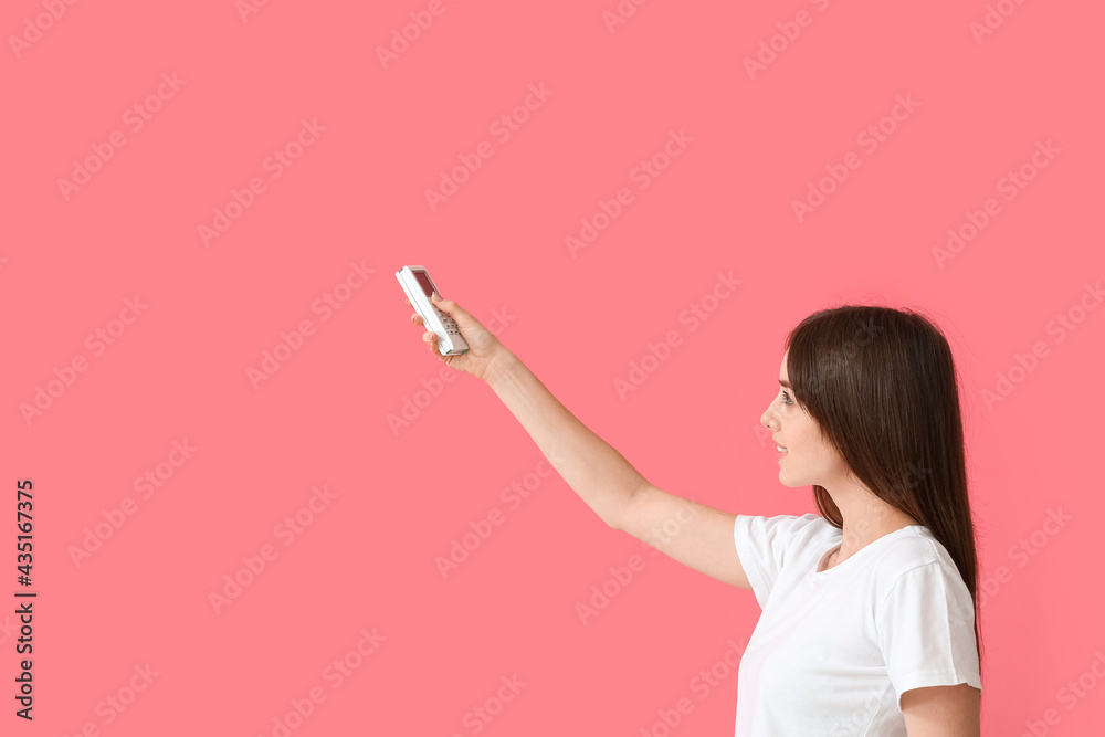 Young woman with air conditioner remote control on color background
