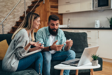 Wall Mural - Young beautiful couple using a laptop and a credit card for an online shopping