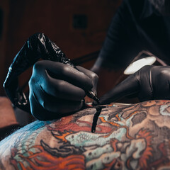 Wall Mural - Tattoo artist hands wearing black gloves and holding a machine