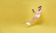 Young asian teenage girl hand holding computer laptop floating in mid-air isolated on yellow background. Fast internet concept.