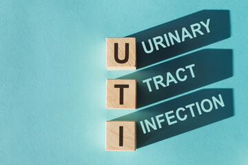 Wooden cubes building word UTI - (abbreviation Urinary Tract Infection) on light blue background.