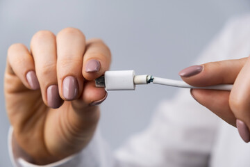 Close-up woman holding torn phone charger type-c wire.