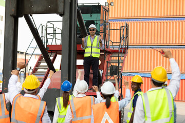 warehouse boss engineer standing on crane car with factory workers raise hand for congratulations in containers warehouse storage