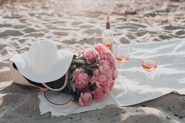 Wall Mural - Picnic with rose wine and peony flowers on the seashore.