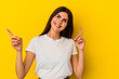© Asier - Young caucasian woman isolated on yellow background pointing to different copy spaces, choosing one of them, showing with finger.