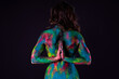 Bright colorful body art on black background, sexy nude woman painted with powder paints