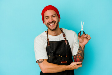 Young tattooed barber man isolated on blue background laughing and having fun.