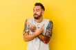 © Asier - Young tattooed caucasian man isolated on yellow background points sideways, is trying to choose between two options.