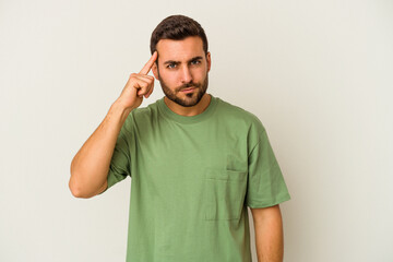 Wall Mural - Young caucasian man isolated on white background pointing temple with finger, thinking, focused on a task.