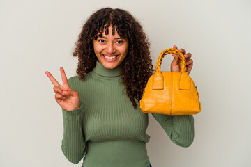 Wall Mural - Young mixed race woman holding a handbag isolated on white background showing number two with fingers.