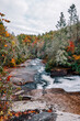 Water from Triple Falls cascades down the stones of the Little River surrounded by colorful fall foliage in DuPont State Recreational Forest, Hendersonville, North Carolina, USA. Long exposure.