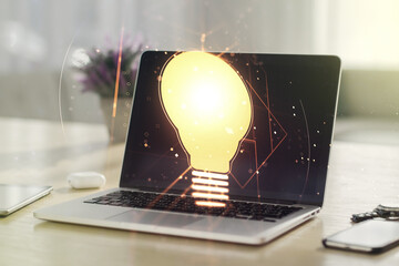 Poster - Creative light bulb hologram on modern laptop background, idea concept. Multiexposure